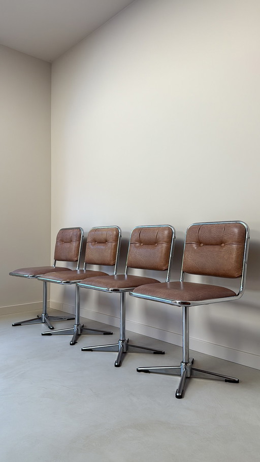 Four vintage chrome swivel chairs with faux leather