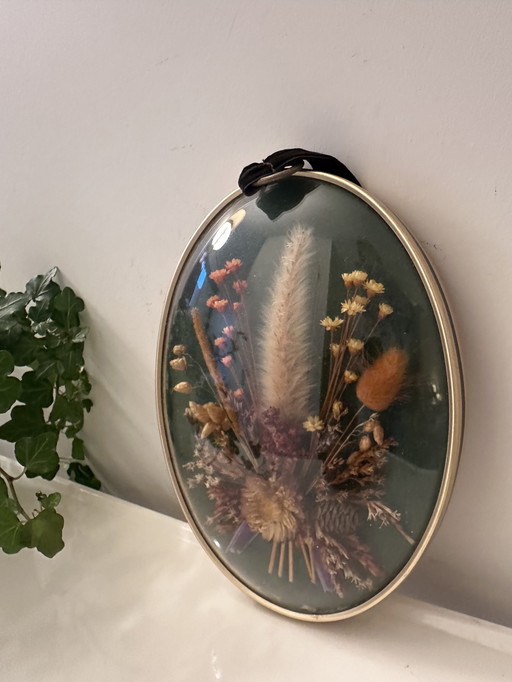 Wall decoration of dried flowers behind curved glass