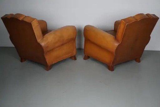 Conjunto de sillones de club franceses de cuero color coñac con respaldos en forma de bigote, años 50