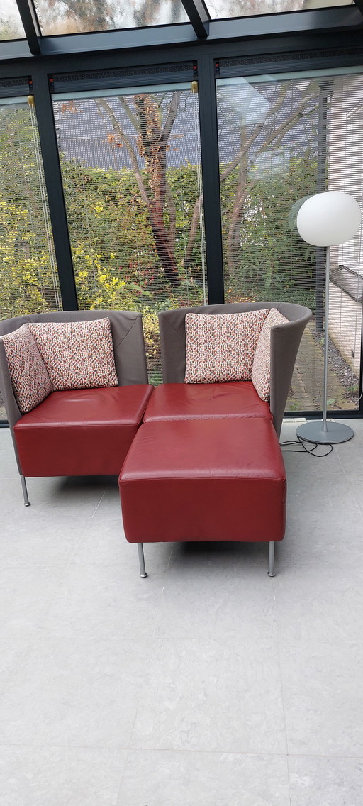 Deux fauteuils Montis Scene avec poufs. Rouges et anthracite, avec de jolis coussins.