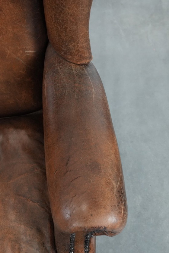 Image 1 of Caratteristica poltrona vintage di grandi dimensioni con ali laterali, realizzata in pelle di pecora.