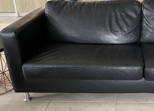 Black leather three-seater sofa.