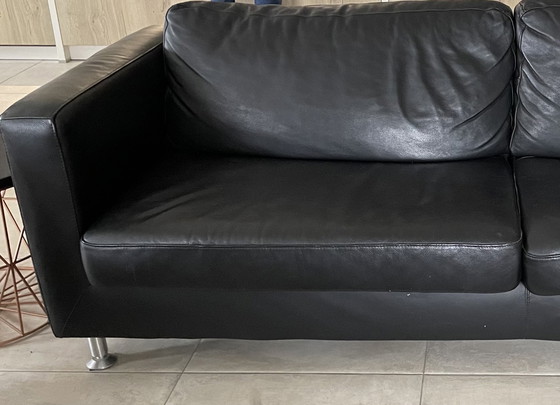 Image 1 of Black leather three-seater sofa.