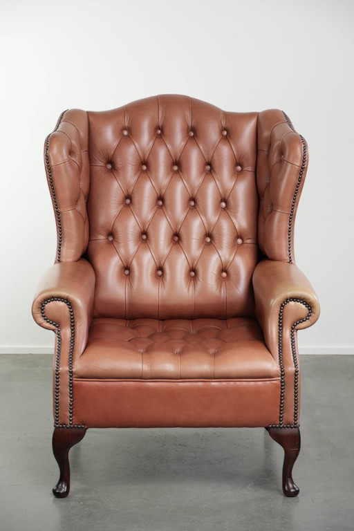 Sillón Chesterfield con orejeras, tapizado en piel de vaca inglesa con botones, una hermosa pátina y preciosos colores.