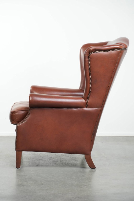 Image 1 of Comoda poltrona a orecchioni in pelle bovina color cognac in stile inglese.