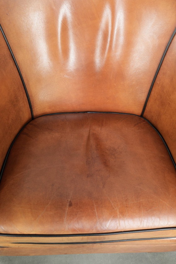 Image 1 of Amplio sillón club de estilo inglés, tapizado en piel de oveja, con acabado de clavos decorativos y ribetes negros.