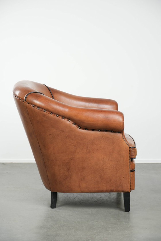 Image 1 of Amplio sillón club de estilo inglés, tapizado en piel de oveja, con acabado de clavos decorativos y ribetes negros.