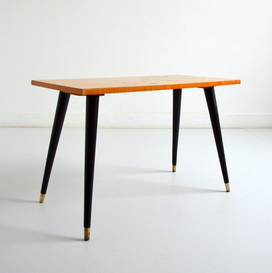 Image 1 of Pretty coffee table from the 50s/60s.  Decorated with a bird on a branch.  Black brass-finish tapered legs.  L 80/ W 40/ H 51