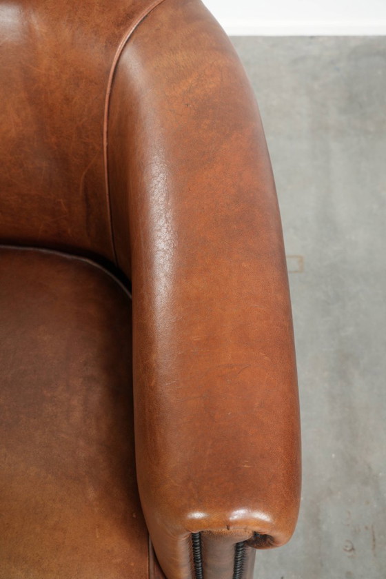 Image 1 of Poltrona club in montone color cognac caldo, rifinita con borchie decorative.