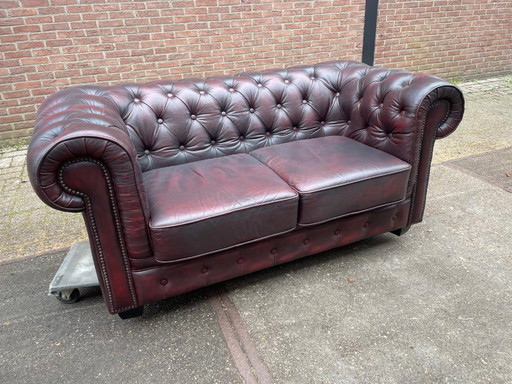 Sofá Chesterfield inglés de cuero color burdeos.