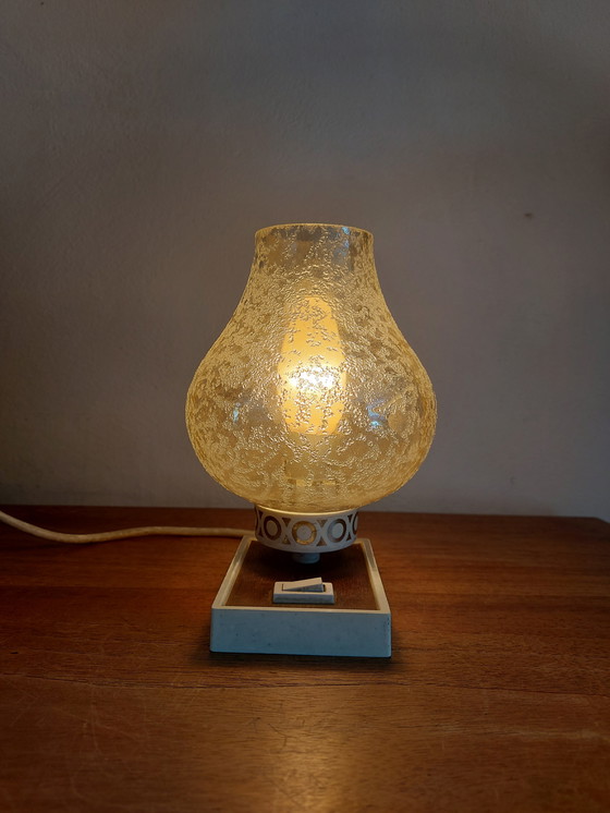Image 1 of vintage tafellamp met een witte basis en een kap van gestructureerd, amber glas. 