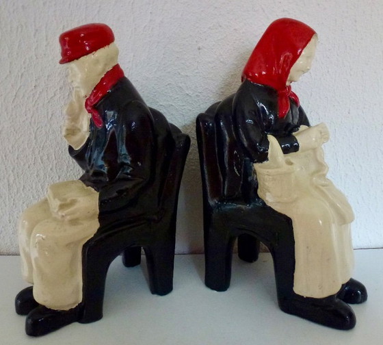 Image 1 of A set of decorative bookends depicting an elderly couple sitting on chairs.