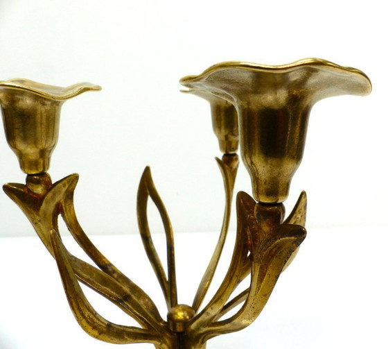 Image 1 of Een paar messing kandelaars met drie lichtpunten op een statief, versierd met organische bloemmotieven, circa 1960-1970.