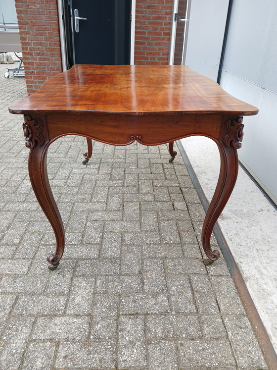 Image 1 of The antique dining table is made of mahogany and has a Louis XV style.