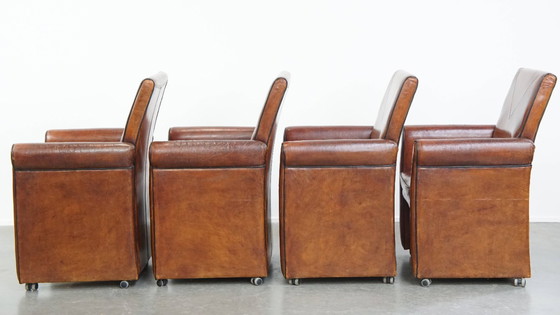 Image 1 of 4 x Vintage schapenleren eetkamerstoel met zwarte biezen op wieltjes