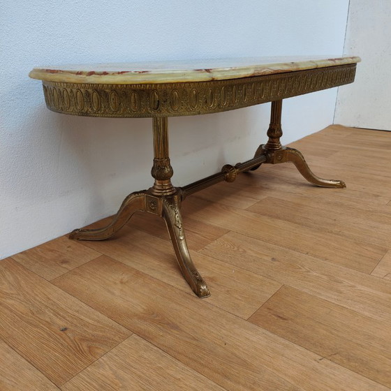 Image 1 of Table basse ovale de style Hollywood Regency avec plateau en marbre et piètement en laiton.
