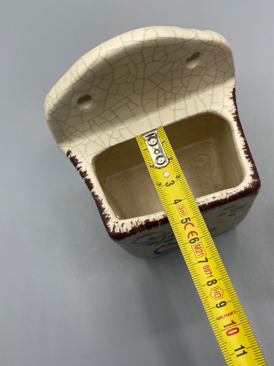 Wandgemonteerde keramische zoutpot met gebarsten emaille en veelkleurige bloemversiering – Frankrijk, circa (photo 7 of 8)