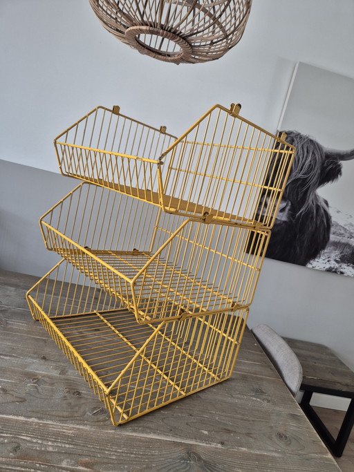 Estantería apilable vintage de metal amarillo.