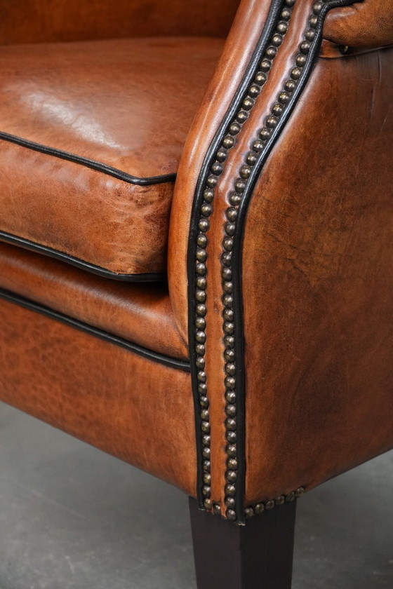 Image 1 of Grote oorfauteuil gemaakt van schapenleer met zwarte biezen en siernagels