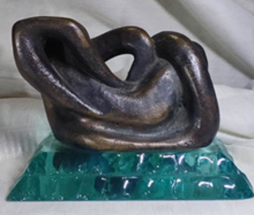 Escultura abstracta de bronce sobre base de vidrio sólido