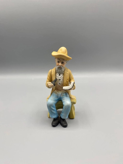 Biscuit figurine, old man sitting reading with pipe, polychrome, country style – beeldhouwkunst