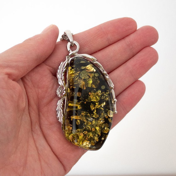 Image 1 of Grande ciondolo in ambra baltica verde: incastonato in metallo color argento con decorazioni floreali.