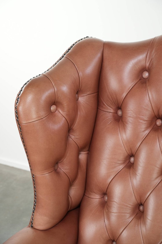 Image 1 of Fauteuil Chesterfield à oreilles en cuir de vachette anglais, assise capitonnée, avec une belle patine et de jolies couleurs.