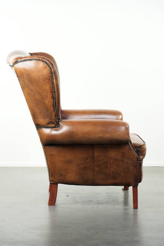 Image 1 of Comfortabele oorfauteuil gemaakt van schapenleer afgewerkt met siernagels en een karaktervolle uitstraling in Engelse stijl