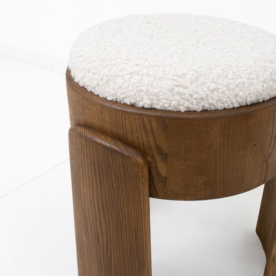 Image 1 of Een paar Art Deco-stijl krukjes van essenhout, bekleed met witte boucléstof.
