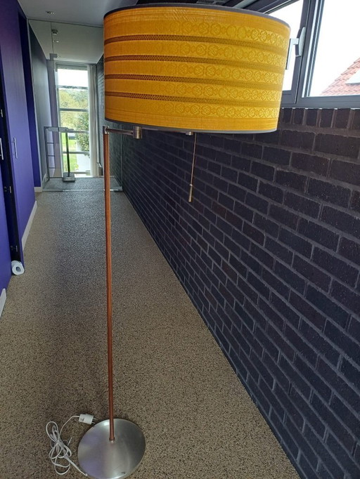 Se trata de una lámpara de pie moderna de nogal de mediados de siglo con una pantalla de tela de color amarillo ocre.