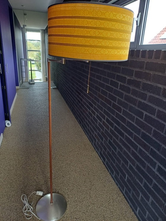 Image 1 of Dies ist eine Stehlampe aus Walnussholz im Mid-Century-Modern-Stil mit einem ockergelben Stoffschirm.