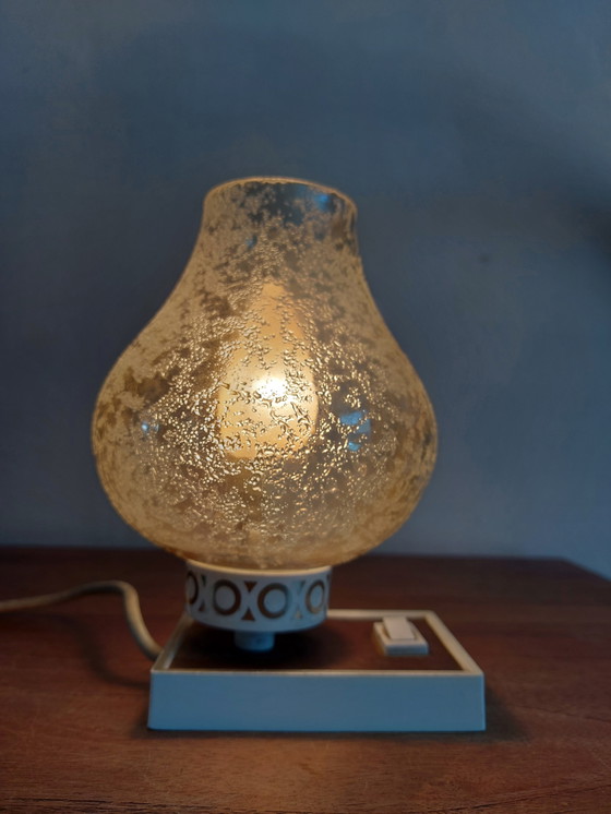 Image 1 of vintage tafellamp met een witte basis en een kap van gestructureerd, amber glas. 