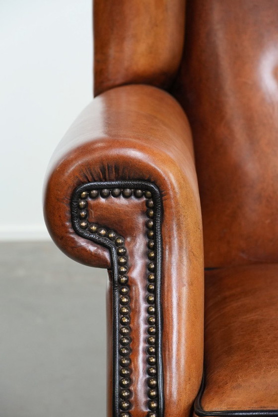 Image 1 of Grote schapenleren oorfauteuil met zwarte biezen en siernagels