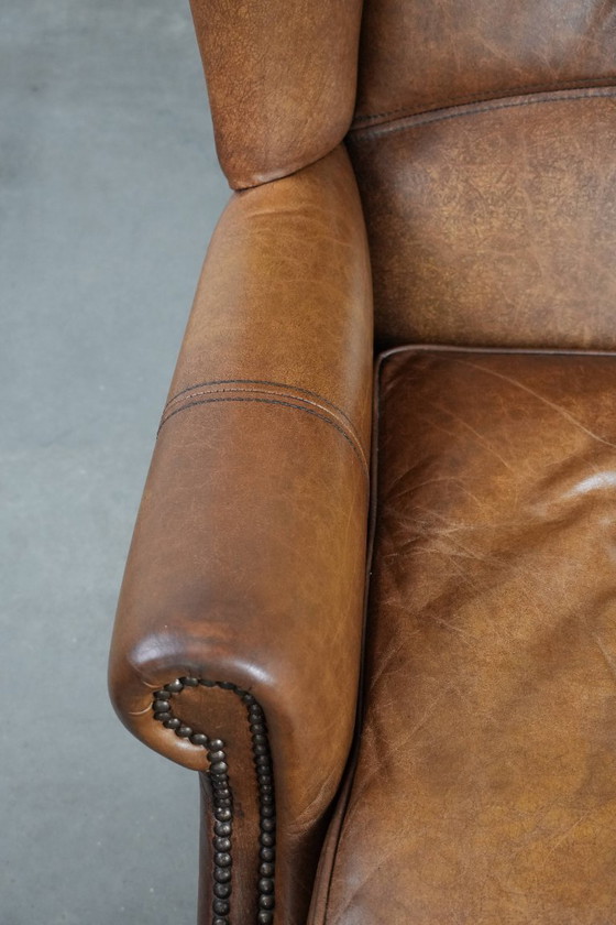 Image 1 of Tijdloze cognac kleurige oorfauteuil in Engelse stijl gemaakt van rundleer afgewerkt met siernagels