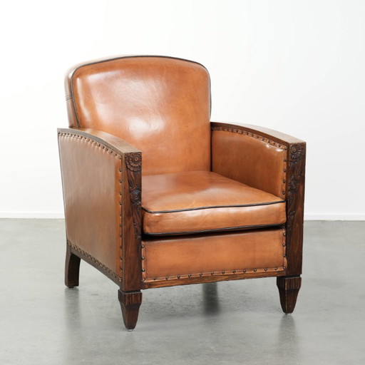 Schapenleren art Deco fauteuil met mooi houtsnijwerk en zwarte biezen