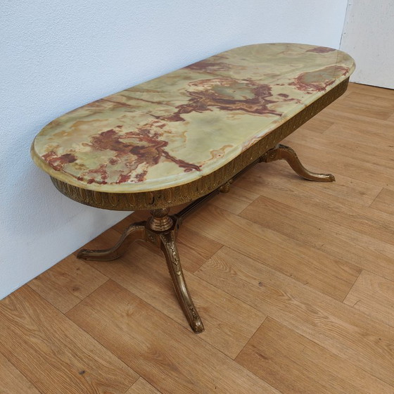 Image 1 of Table basse ovale de style Hollywood Regency avec plateau en marbre et piètement en laiton.
