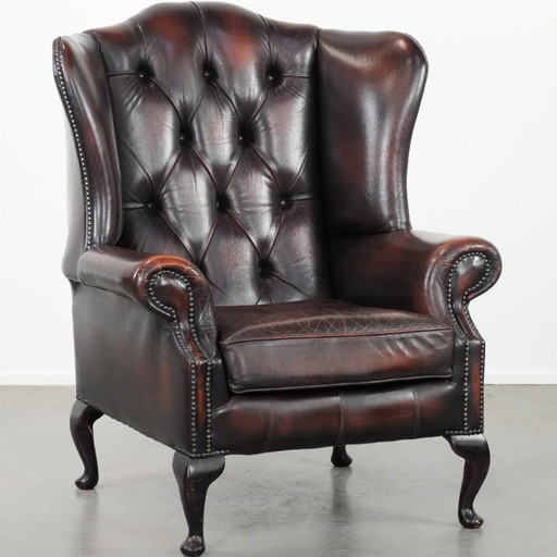 Poltrona Chesterfield con braccioli in pelle bovina marrone, in classico stile inglese.