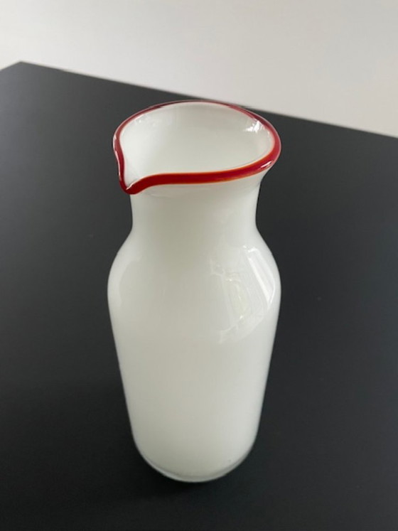 Image 1 of Caraffa dal design scandinavo in vetro bianco con bordo rosso.
