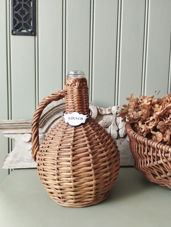 Image 1 of Kleine glazen demijohn, geweven rieten envelop, Kirsch emaille etiket