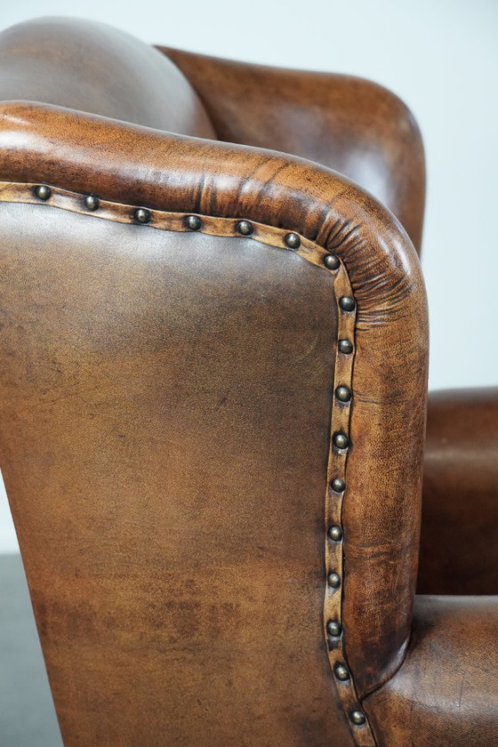 Image 1 of Comfortabele en tijdloze schapenleren oorfauteuil met siernagels en zwarte biezen