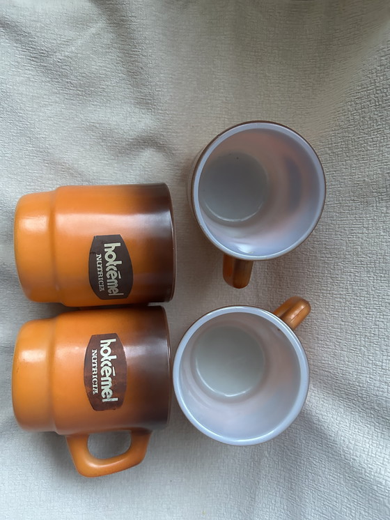 Image 1 of Dit is een set vintage Hotcemel Nutricia kopjes of mokken van oranje opaalglas met een kleurverloop.