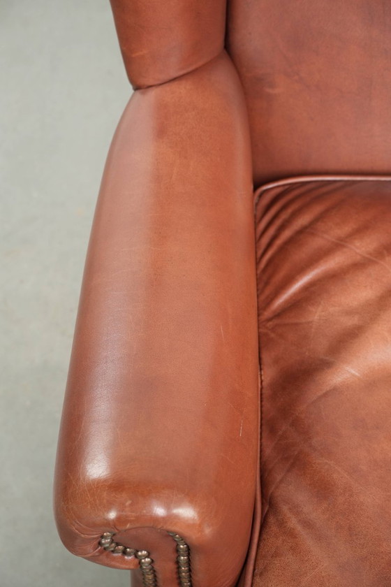 Image 1 of Comoda poltrona a orecchioni in pelle bovina color cognac in stile inglese.