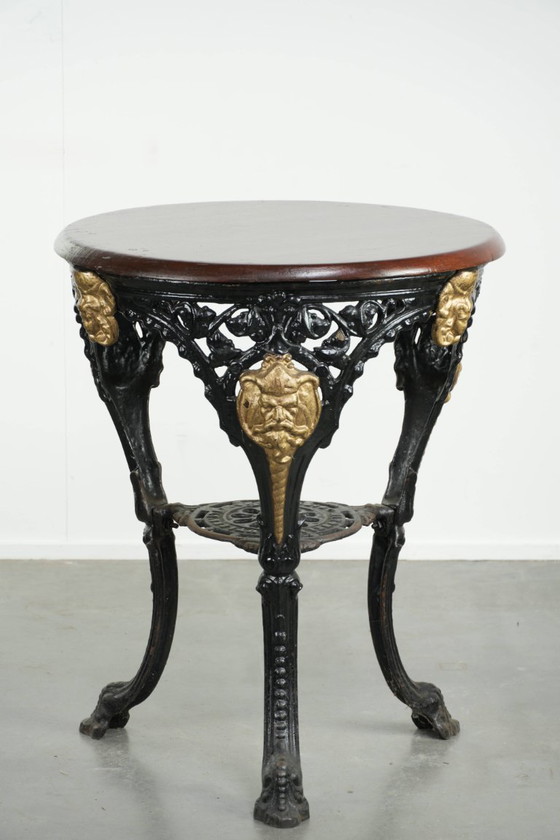 Image 1 of Antieke Engelse bistro/ bijzettafel met een gietijzeren onderstel uit begin 20e eeuw en een massief houten tafelblad