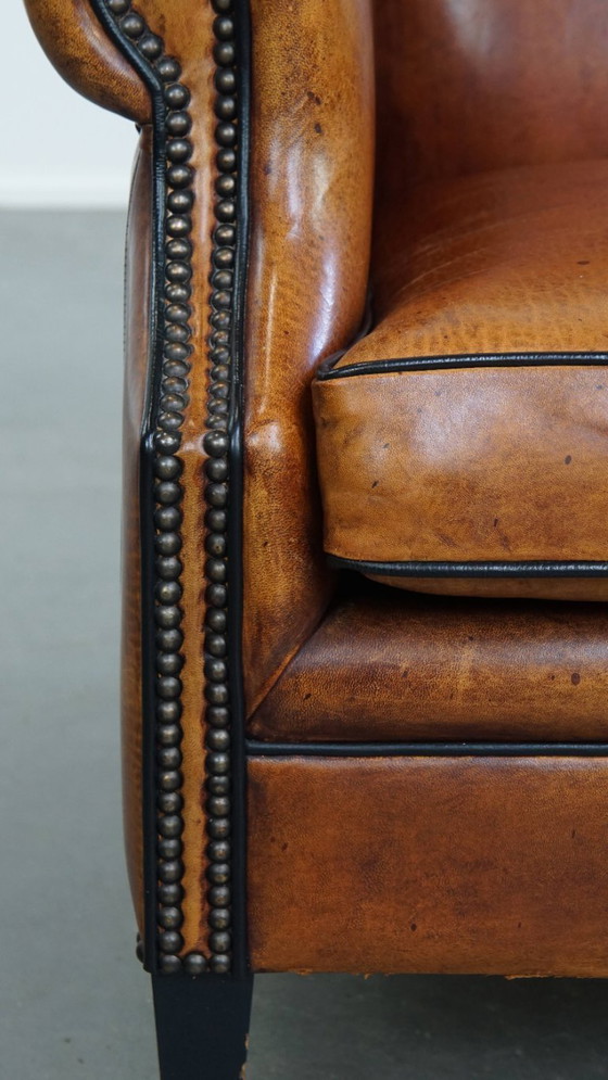 Image 1 of Comfortabele schapenleren oorfauteuil met een prachtige warme kleurstelling en een afwerking met stiksels en zwarte biezen