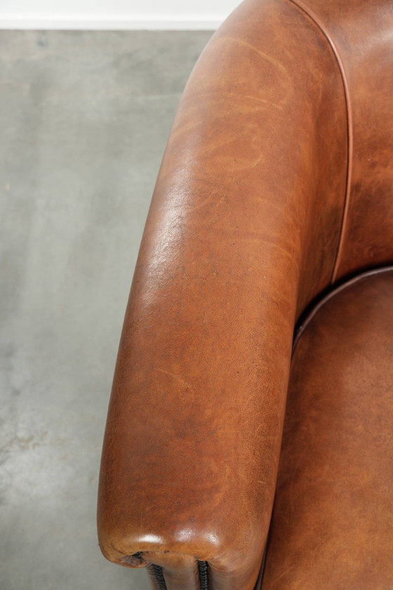 Image 1 of Poltrona club in montone color cognac caldo, rifinita con borchie decorative.