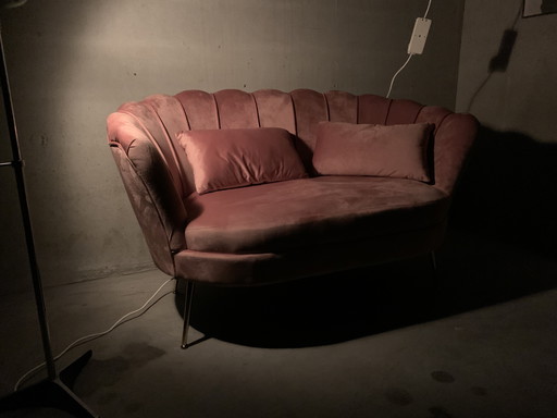 Banc rose à deux places avec des pieds dorés.