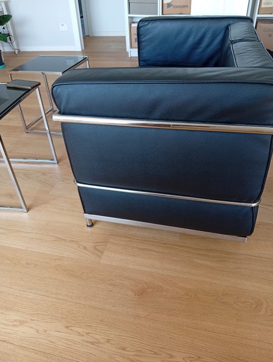 Image 1 of Een set van twee zwarte leren fauteuils en een bank.