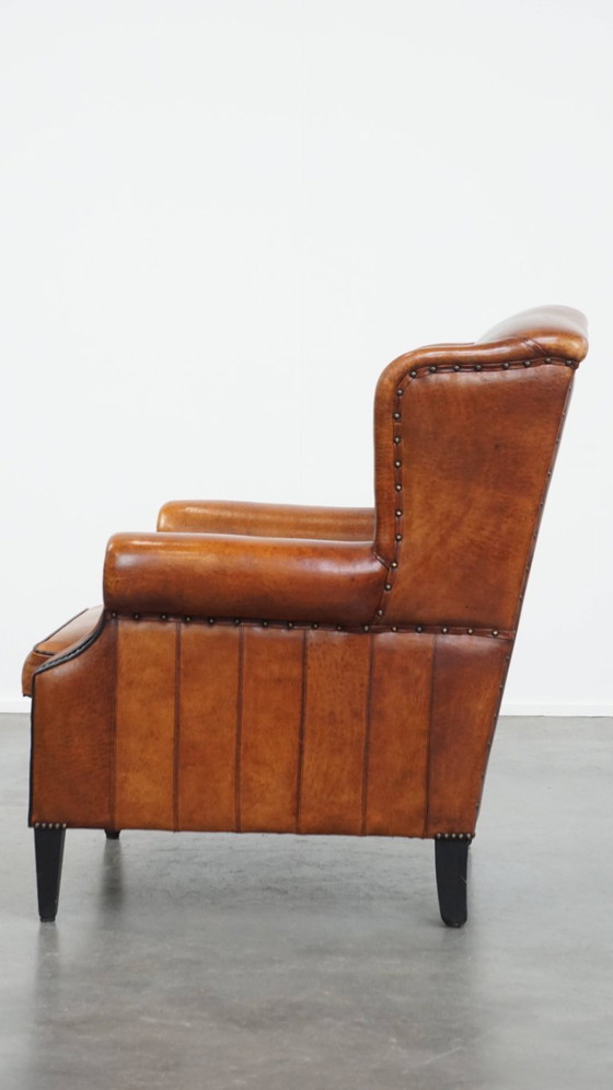 Image 1 of Comfortabele schapenleren oorfauteuil met een prachtige warme kleurstelling en een afwerking met stiksels en zwarte biezen