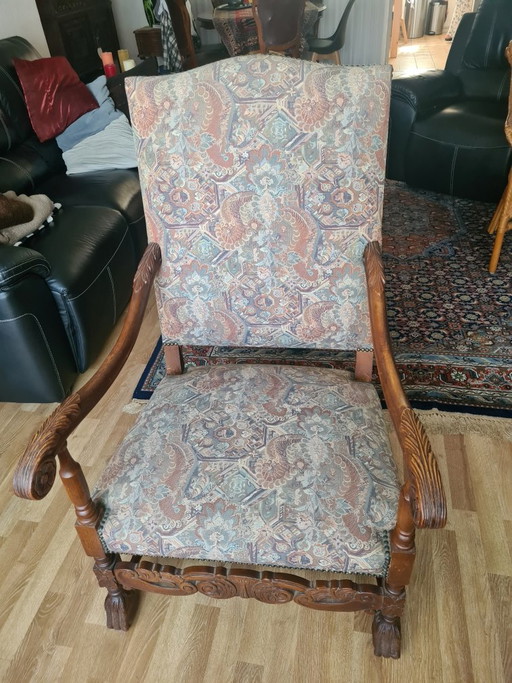 Sillón antiguo de madera noble con tapicería de tapiz.