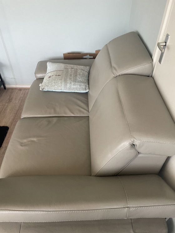 Image 1 of Grijze leren bank met verstelbare hoofd-arm leuningen.